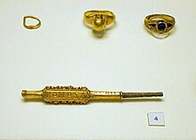 Two godlen rings, one with a stone, an earring and a pin decorated with small spirals