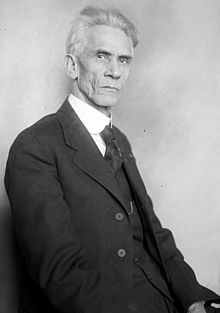 Aged gentleman in three-piece suit, staring at the camera.