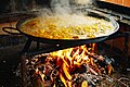 Paella being cooked on a wood fire in the middle of the road