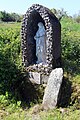 Antiker Kreuzstein mit Swastika neben einer modernen Ädikula-Heiligenfigur am katholischen Wallfahrtsort der St. Brigid Quelle bei Cliffoney, County Sligo in Irland