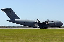Colour photo of a grey military aircraft on the tarmac of an airport
