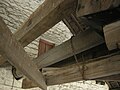 Massive oak drive shaft of mill passing through wall of threshing barn, supported on both sides by two heavy oak beams fixed between the mill's own tie beam and the threshing barn wall