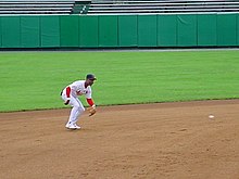 Player fielding a ground ball on a dirt infield