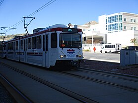 A TRAX light rail train with a sign displaying "UTA" in blue text.