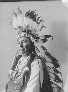 A portrait of Chief Joseph facing left, wearing a feathered headdress.