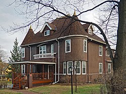 Two-and-a-half-story house with corner turrets, fishscale shingling, and a projecting porch