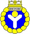 a shakefork—Azure, a shakefork argent supporting in the middle chief a bezant, within an annulet enwreathed, ensigned of a naval crown or, the sails argent, beneath which on a panel argent edged or is the name "Discovery" in letters sable—HM Canadian Ship Discovery