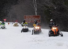 Photograph showing snowmobiles using a snow-covered H-58