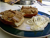 A chopped liver meal on bagels with sour cream herring and onions