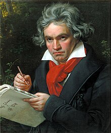 Man with grey hair holding a pen and a score