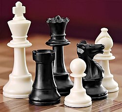 A selection of white and black chess pieces on a checkered surface.