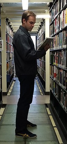 Rugg holding books in a library