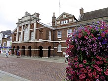 red brick building, colonaded at ground level with white pillars at the front above
