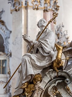 St Giles holding a crozier and comforting his arrow-shot doe