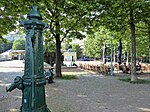 Henriettenplatz, Sitzplätze vor dem Restaurant und historische Wasserpumpe