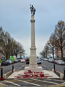 Bronze statue atop a decorative column in the centre of a wide road