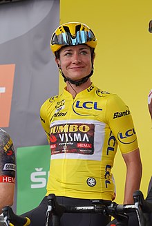 Woman in yellow jersey smiling for photographers