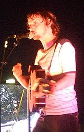 Kid Harpoon performing with a microphone and guitar