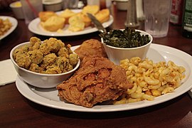 A traditional southern food dinner consisting of fried chicken with macaroni and cheese, collard greens, okra and cornbread