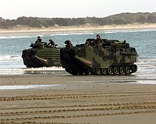 Two U.S. Marine Corps Assault Amphibious Vehicles emerge from the surf onto the sand of Freshwater Beach, Australia