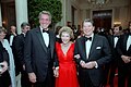 President Ronald Reagan and First Lady Nancy Reagan pose with actor Rock Hudson while guests mingle in the Cross Hall prior to a state dinner, 1984