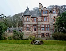 A large, grey stone, house with red sandstone dressings
