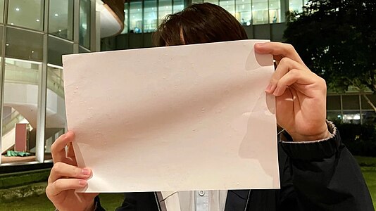 A University of Hong Kong student holds up a blank piece of paper to show support for the people in mainland China protesting against the COVID lockdown in 2022.