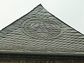 Slate roofers guild emblem as an ornament made with slate roof shingles, Meerbusch, Germany. Note the hip shingles act as a ridge cap.