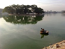 A lake with an island. A fisherman in a coracle visible.