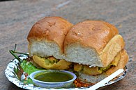 Vada pav served with a side of green chili pepper garlic chutney