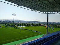 A natural grass pitch and the swimming pool near the main stadium