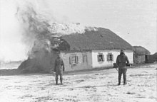 Two Waffen-SS look at a burning farmer's house near Kharkov, February 1943