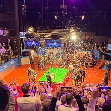 Image of confetti falling on a snooker table as Selby holds a trophy