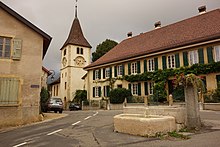 A road with a church and terraced houses in Bôle, Switzerland
