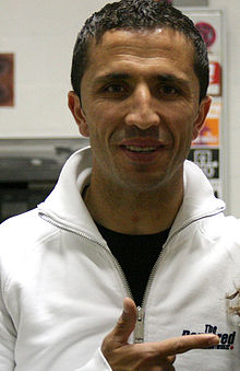 A man with dark hair wearing a white tracksuit