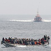 Boat overloaded with illegal immigrants, alongside a Spanish coast guard.