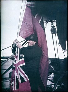 A portrait of Alfred Cheetam with flags on board the ship Endurance