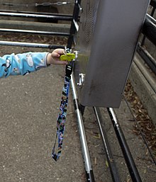 A small child holding a yellow elephant key, inserting it into a slot on a metal box.