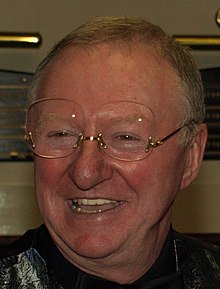 A headshot of Dennis Taylor smiling