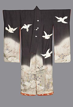 A closed, long-sleeved black uchikake viewed from the front. It is lined in coral-coloured fabric, with a thickly-padded hem embroidered with cherry blossoms and leaves. The kimono fades to white from the waist down and from the lower third of each sleeve. The top of the kimono displays a number of white hawks. The bottom of the kimono is decorated with a court garden pattern seen through hazy clouds. The left side of the collar has embroidered cherry blossoms on the centre.
