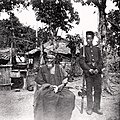 Image 11Temne leader Bai Bureh seen here in 1898 after his surrender, sitting relaxed in his traditional dress with a handkerchief in his hands, while a Sierra Leonean West African Frontier Force soldier stands guard next to him (from Sierra Leone)