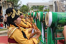 Women in yellow playing green drums