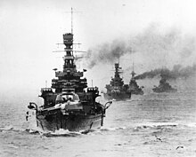 A battleship steaming towards the camera; three others are strung out behind