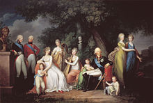 A family in a park. On the left, two young men in military uniforms sand next to a bust of Peter the Great. Then sits a woman in white, caressing a little boy in white with a blue belt. Then two girls in white, the second playing the harp, with the bust of a small girl above them. The father sits next in a military uniform, caressing a little girl in green, and a small boy sits next to his chair. Two young women, one in greenish yellow and the other in blue, stand on his right.