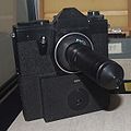 Kamera mit Sonderobjektiv SO-3.5.1 zum konspirativen Fotografieren. Das Objektiv konnte auf eine geräuscharme Spiegelreflexkamera geschraubt werden. Damit war es möglich, durch ein Loch von 1 mm Durchmesser zu fotografieren.[92]