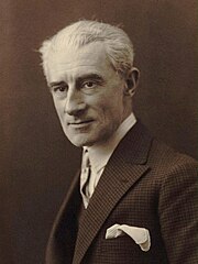 Clean shaven white man with full head of white or grey hair, elegantly dressed