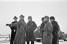 A group of foreign journalists observes something during snowfall in Mainila, where a border incident between Finland and the Soviet Union escalated into the Winter War.