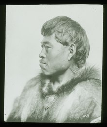 A Inuit man in a parka with a mustache looking to his right.