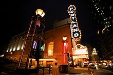Building at night, illuminated by interior and exterior lighting, including a neon marquee sign that reads "Portland" vertically.