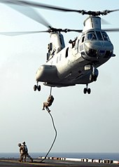 Marines descending from a helicopter with no equipment other than a rope
